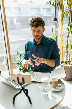 Businessman gesturing while discussing on video call through smart phone at table in cafe