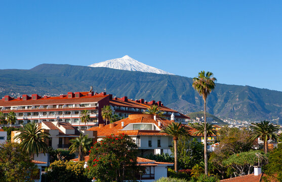 Spain, Province of Santa Cruz de Tenerife, Puerto de la Cruz, Buildings of coastal city in summer with Mount Teide looming in distant background