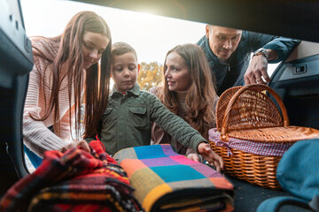 Family picking up picnic stuff from car trunk