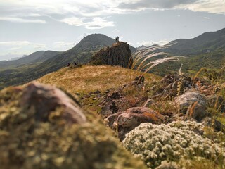 Summer landscape with a couple looking at the scenery on the rock. Travel destinations and hiking goals achievement for good health and strong body