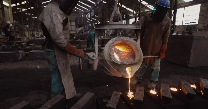 AFRICA,SOUTH AFRICA,CIRCA 2020.  Factory workers pouring molten metal into casts at a steel casting foundry