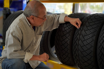 Male customer and tire salesperson with clipboard showing tires at a repair service center or a tire shop, business idea.