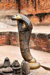 Bronze statues of the mythical Shesh nag guard in a temple pond in Bhaktapur, Kathmandu