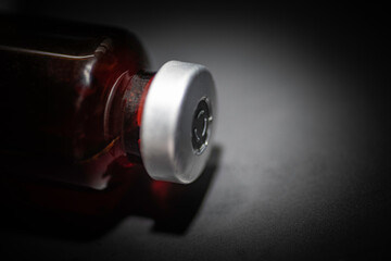 Macro Shot Of Amber Vaccine Vial In Black Background