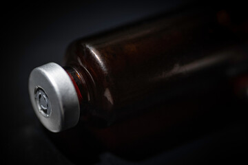 Macro Shot Of Amber Vaccine Vial In Black Background