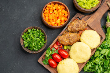 Close up view of dinner background with tasty cutlets vegetables and greens on dark background