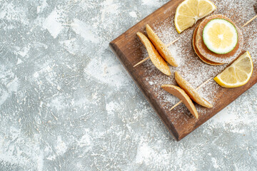 Half shot of classic pancakes with lemons on wooden cutting board on blue background