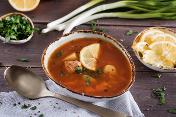 Tomato soup with red fish, a traditional Balkan dish. Beautiful table setting, lemon, herbs. Ukha, Serbian, Montenegrin, Croatian dish.