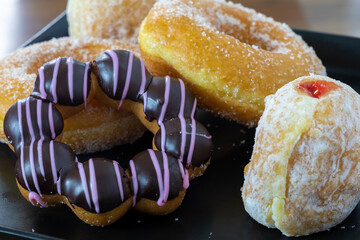 Ring and jam filled donuts on a black plate, soft focus
