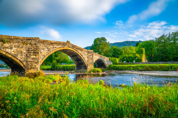 Fototapeta na wymiar Stone bridge across the river Conwy and old cottage covered with vine leaves, Llanrwst, Caernarfon, North Wales