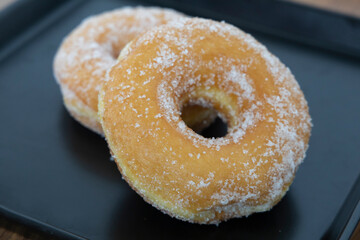 2 ring donuts on a black plate, soft focus