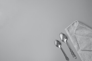 Top view of two silver spoons and a gray napkin in a gray background with copy space