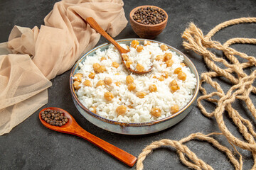 Close up view of peas and rice dish with a spoon and pepper in a bowl and spoon on dark background