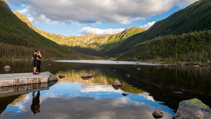 Fototapeta premium Young couple kissing in front of the lake of the Americans, in the Gaspésie national park, Canada
