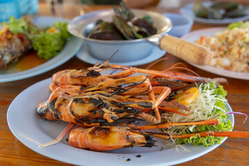 Grilled shrimps  in front, steamed mussels, fried fish and fried rice. Thai seafood menu