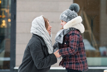 Little daughter looking at mother with love in winter city