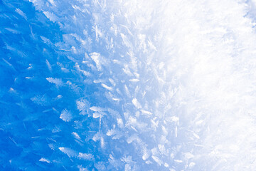 Close-up clean snow and ice crystals unevenly illuminated from the side by the bright sun in December in Russia as a natural background