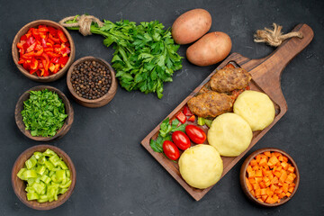 Close up view of tasty cutlets with vegetables and a bunch of green on dark background