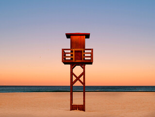 life guard watchtower on an empty beach during sunrise