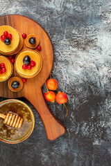 Vertical view of stack of pancakes with fruits and honey