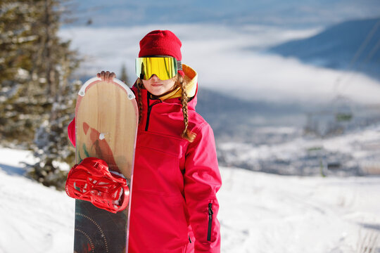 Woman snowboarder poses with board.