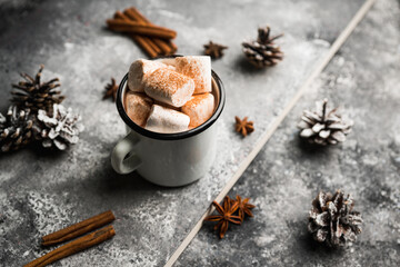 Vintage white metal cup with hot chocolate and marshmallow on the rustic background. Hygge winter evening. Selective focus. Shallow depth of field. 