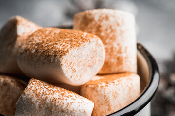 Vintage white metal cup with hot chocolate and marshmallow on the rustic background. Hygge winter evening. Selective focus. Shallow depth of field. 