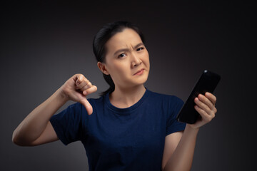 Asian woman looking at smart phone and showing thumb down.