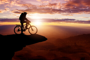 Fototapeta na wymiar Silhouette of a Cyclist on the top hills and sky sunset background