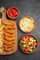 Fried chicken with potatoes different spices and sauerkraut with salad on dark table
