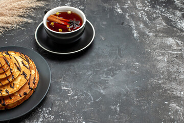 Horizontal view of delicious pancakes with chocolate and a cup of cinammon tea on gray background