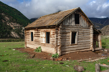 Fototapeta premium Beautiful wooden abandoned log house on mountains background