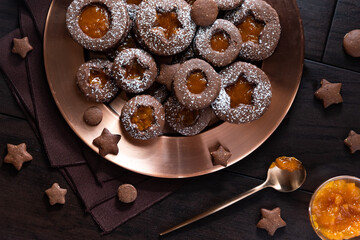 Obraz na płótnie Canvas Top down view of chocolate Linzer cookies filled with apricot preserves on a copper tray.