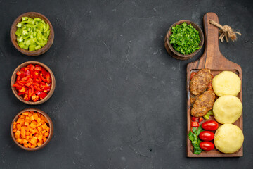 Horizontal view of dinner background with tasty cutlets vegetables and greens on dark background