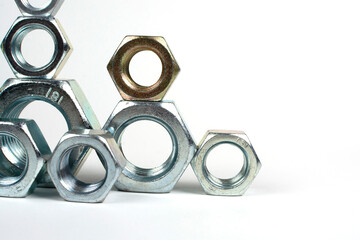 many metal nuts stacked on a white background