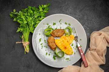 Overhead view of well-cooked cutlet meal and a bunch of green