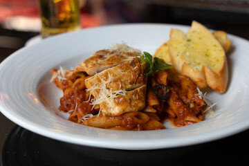 Grilled Chicken in a spicy chili and olive tomato sauce served with penne pasta, garlic bread and parmesan