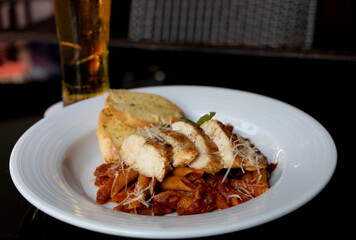Grilled Chicken in a spicy chili and olive tomato sauce served with penne pasta, garlic bread and parmesan