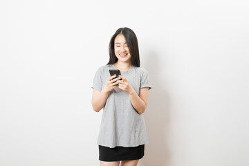 Beautiful Asian woman standing and smile using mobile smart phone looking to camera on a white background.