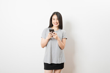 Beautiful Asian woman standing and smile using mobile smart phone looking to camera on a white background.