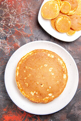 Vertical view of Classic American homemade pancakes on white plates on mixed color table