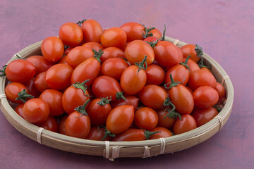 Cherry tomatoes in a basket isolated on pink.