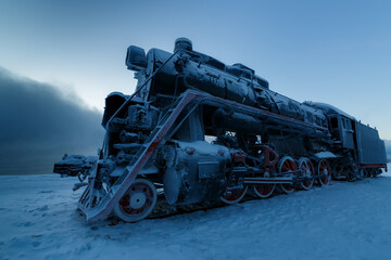 Old steam locomotive in winter covered with rime, side view
