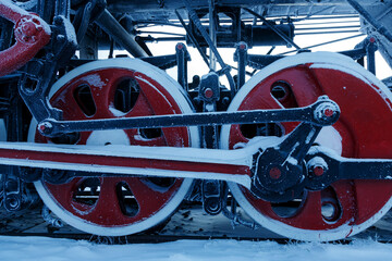 Red wheels of old steam train covered with snow and hoarfrost