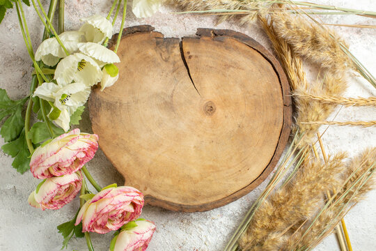 overhead shot of wooden platter and emmers and flowers around it on marble background