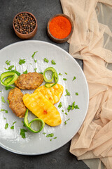 Delicious homemade cutlet meal along with potatoes and different spices next to towel on dark table