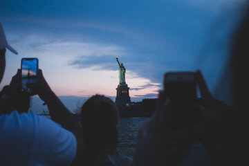 People taking a photo of Statue Of Liberty at sunset