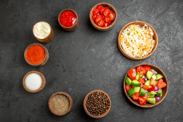 Obraz na płótnie Canvas Top view of different spices sauerkraut salad mayonnaise and ketchup on dark table