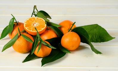 Mandarins with leaves on the white wooden background.