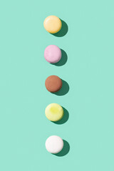 Assorted macaroons on bright blue green colored background, colorful french cookies macarons.